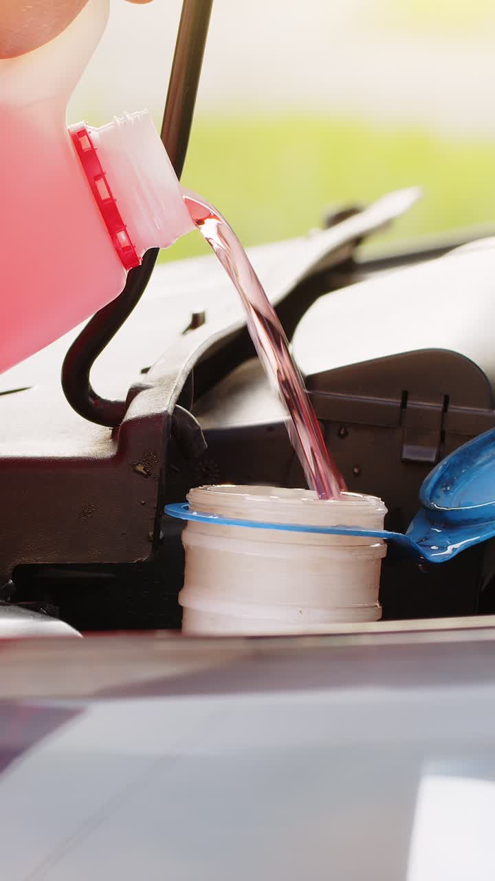 서비스 직원 남자는 자동차 유체 앞유리 빨간색 청소 세탁기 유리 여름 또는 겨울 청소기를 붓습니다