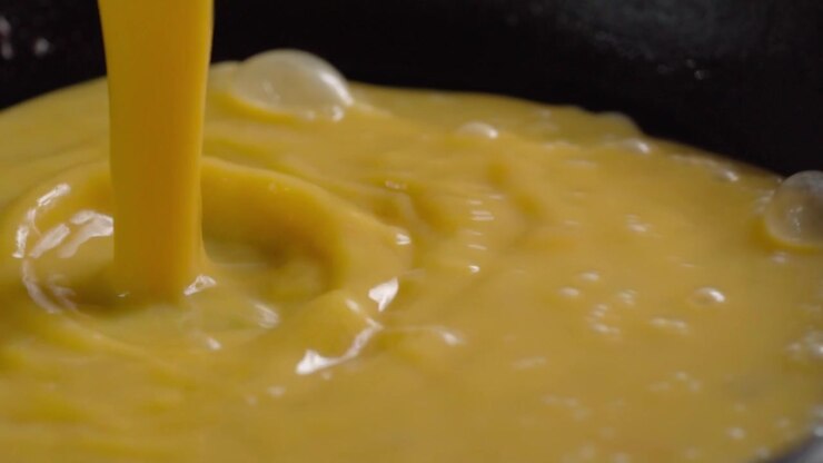 Closeup of batter pouring into hot pan during hotcake preparation, spreading across heated surface while cooking begins in kitchen for homemade breakfast