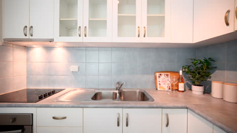 pullback from staged kitchen countertop with candles decorative book and plant opposite electric stovetop kitchen