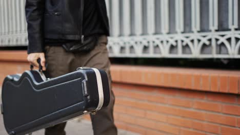 Man-stroll-down-the-street-with-a-guitar-case