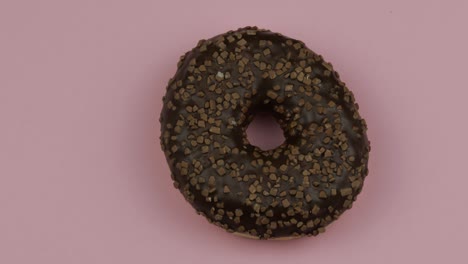 sweet donut rotating on pink background. top view. tasty, fresh sprinkled donut