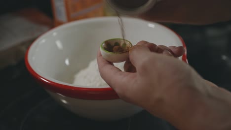 pouring cinnamon powder in a measuring spoon - cookie ingredients - close up