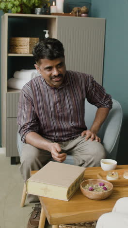 man sitting at a table with candles and herbs