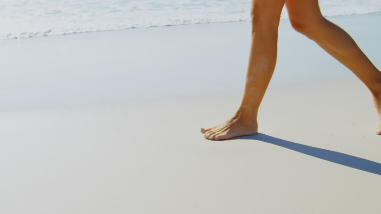 Primo piano sulle gambe di una donna che cammina in spiaggia in una giornata di sole 4k