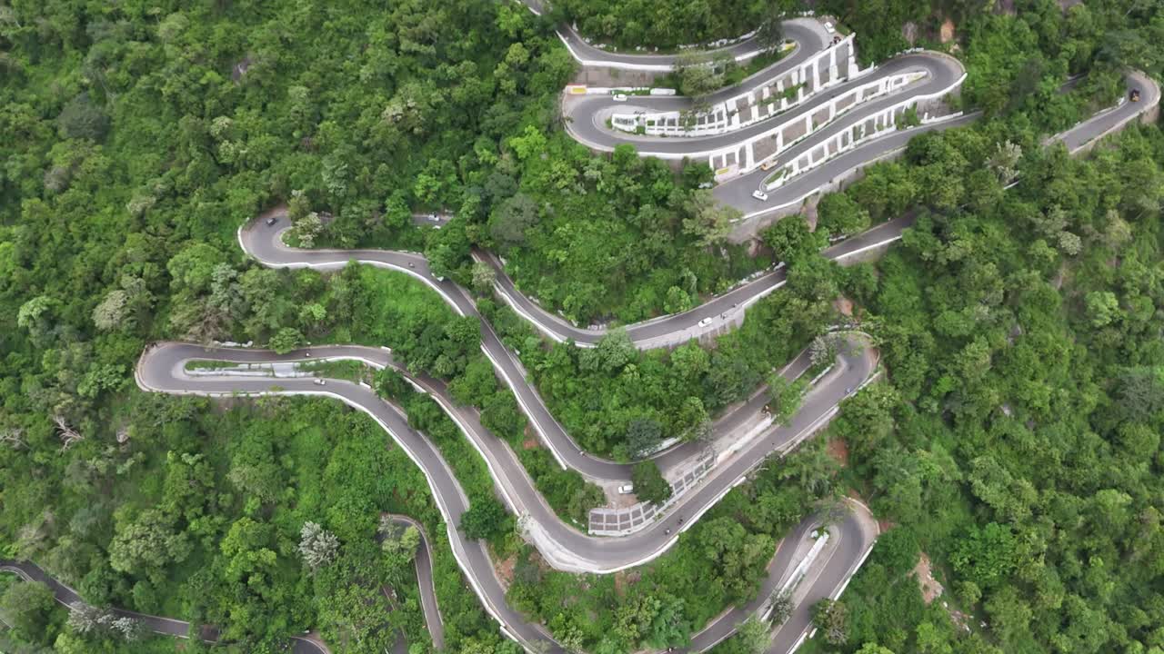 Drone shot of the serpentine ghat road at Kolli Hills, one of India's most challenging drives. The road is carved into the tropical, thick Eastern Ghats vibrant tropical forests