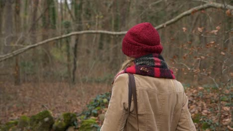 Circling-behind-woman-in-red-hat-walking-in-autumn-forest,-Slow-Motion