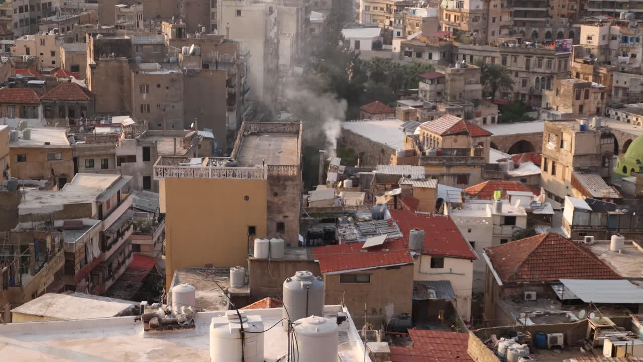 Vista aerea di un centro storico di una città araba con fumo che sale dalla città a Tripoli, Libano settentrionale.