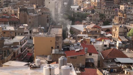 aerial view of an old town of an arab city with smoke rising from the city in tripoli, northern lebanon