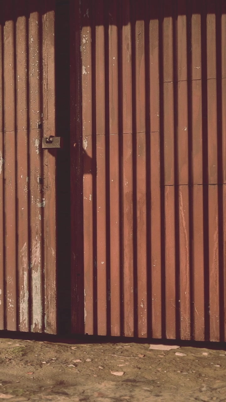 Rusty metal door with shadows at a construction site in the afternoon