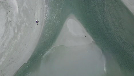 a lagoon flows into the ocean with sandy islands as seen from above