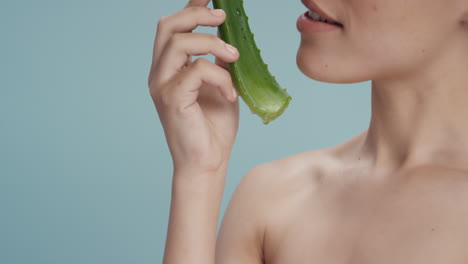 Primer-Plano-Retrato-Hermosa-Mujer-Joven-Sosteniendo-Aloe-Vera-Goteando-Agua-Disfrutando-De-Esencia-Natural-Fresca-Mujer-Juguetona-Sonriendo-Sobre-Fondo-Azul-Concepto-De-Cuidado-De-La-Piel