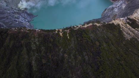 drone flyover crater rim of ijen volcano, reveal acid lake and cone shape volcano. indonesia travel