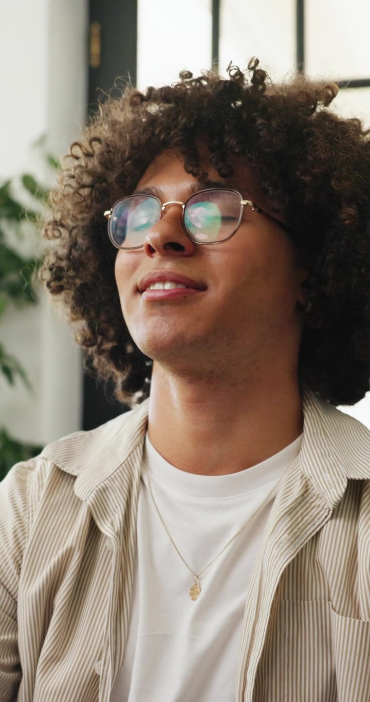 Young Man With Curly Hair Smiling Thoughtfully