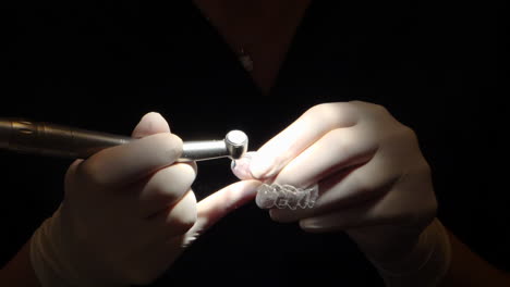 close-up view of orthodontist costuming an invisalign aligner, in dark setting with focus light