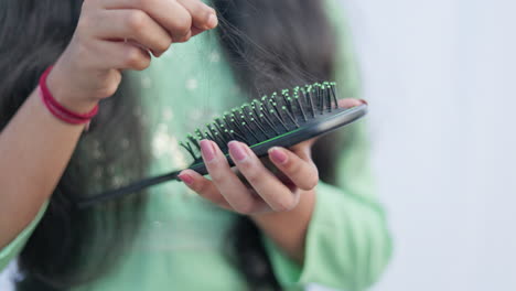crop view of woman removing fallen hair from the comb.