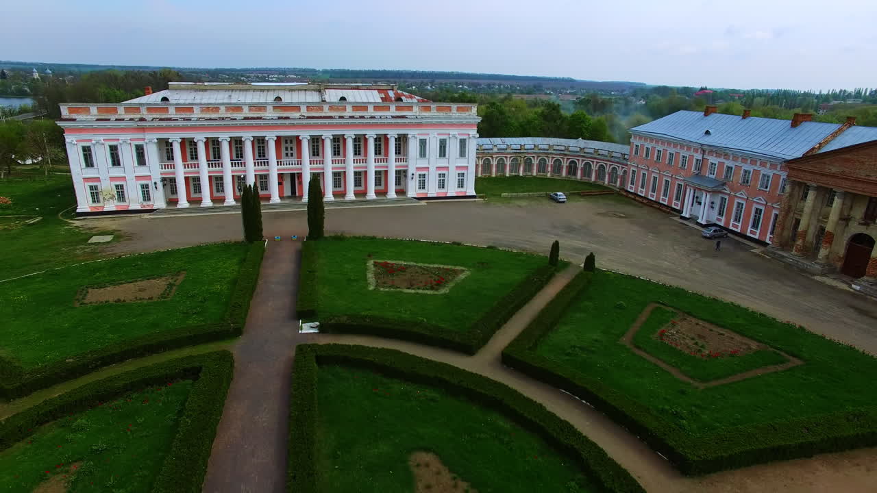 Magnificent old-fashioned palace with white columns. Drone distancing from a building over the well-kept territory.