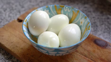 hard boiled egg in a colorful bowl over a wooden chopping board