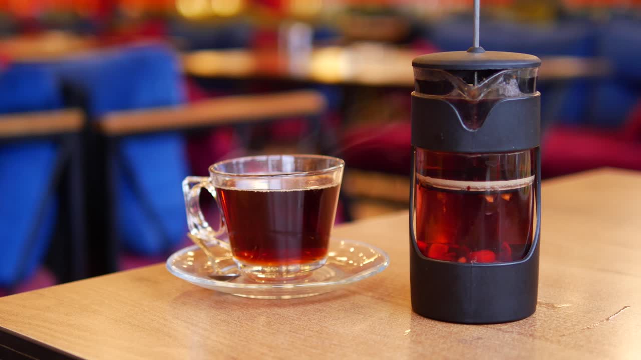 Cup of tea and tea infuser on a table in a cafe