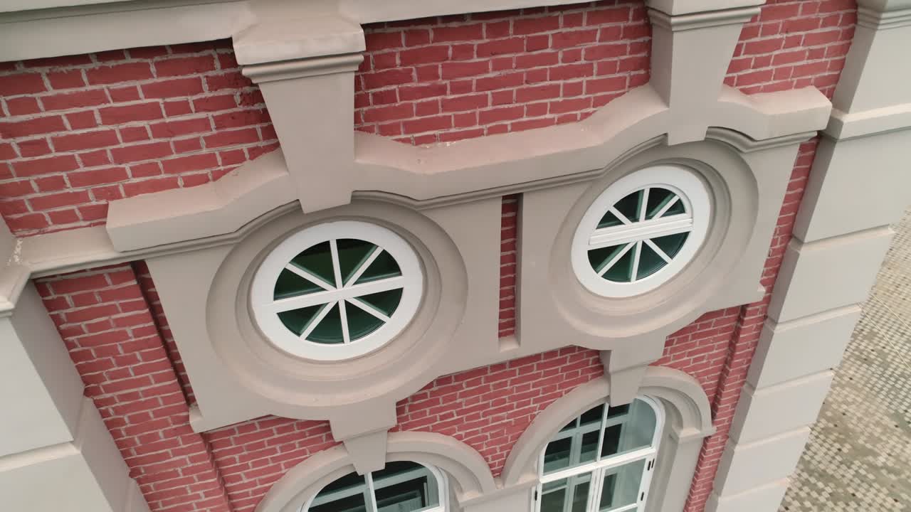 edificio de ladrillo rojo con ventanas redondas y ornamento clásico