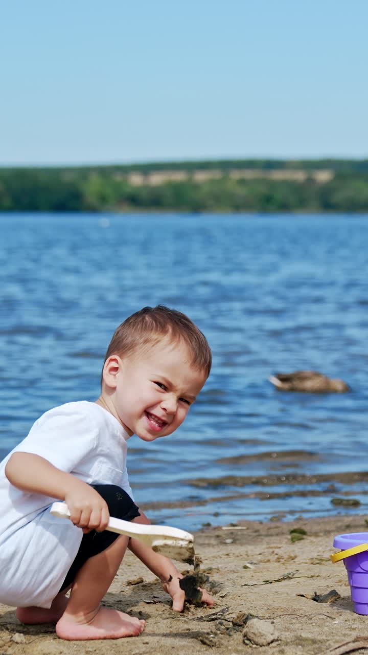 Small boy on river beach playing. Little child summer lifestyle. Vertical video