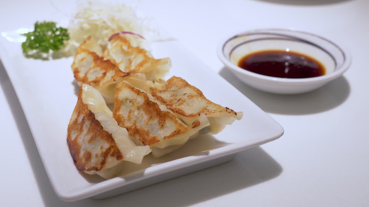Chopsticks dipping a dumpling into a sauce mix and taking the food into somebody's mouth enjoying the meal, Pattaya, Chonburi province, Thailand