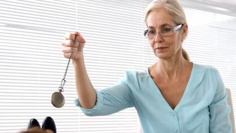 Hypnotist-holding-a-pendulum-on-her-patient