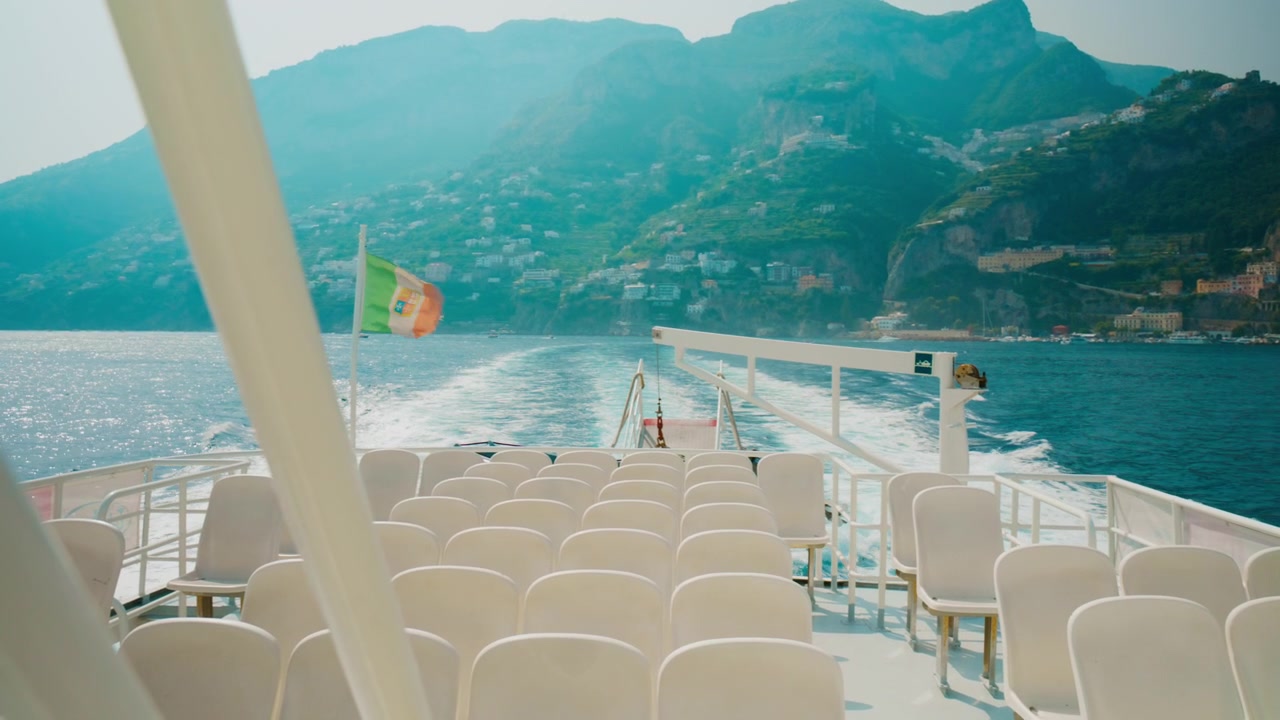 Rækker af tomme plastikstole vendt mod kølvandet fra en færge til Amalfi