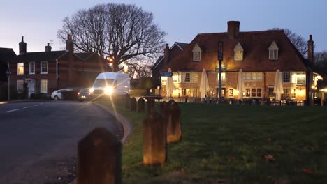 Toma-Nocturna-De-Tráfico-Con-Faros-Deslumbrantes-En-Un-Bonito-Pueblo-De-Kent-En-Inglaterra