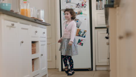 happy little girl dancing in kitchen having fun waving maginc wand playing pretend doing funny dance moves enjoying weekend at home