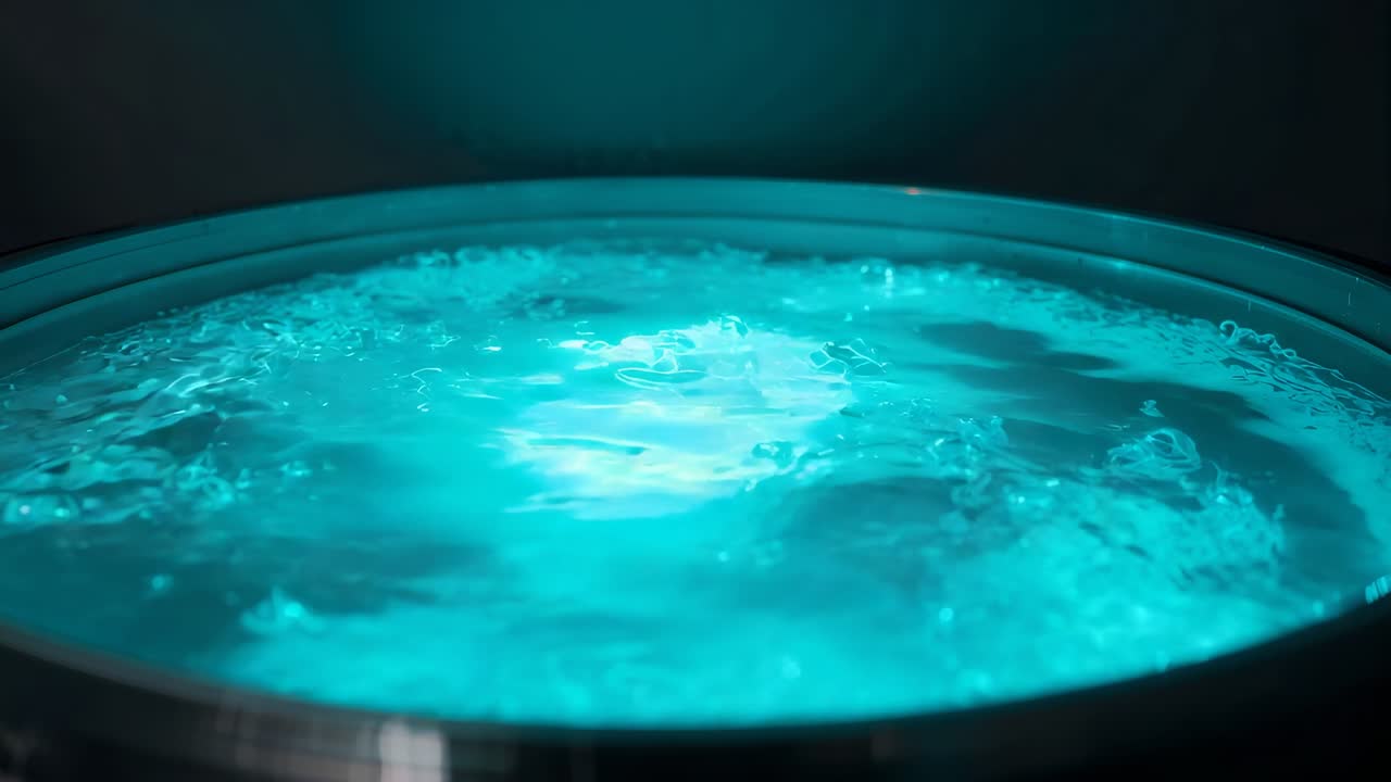 Vasca metallica radiante con liquido turchese illuminato in una stanza buia, che forma bolle e una patina sul bordo