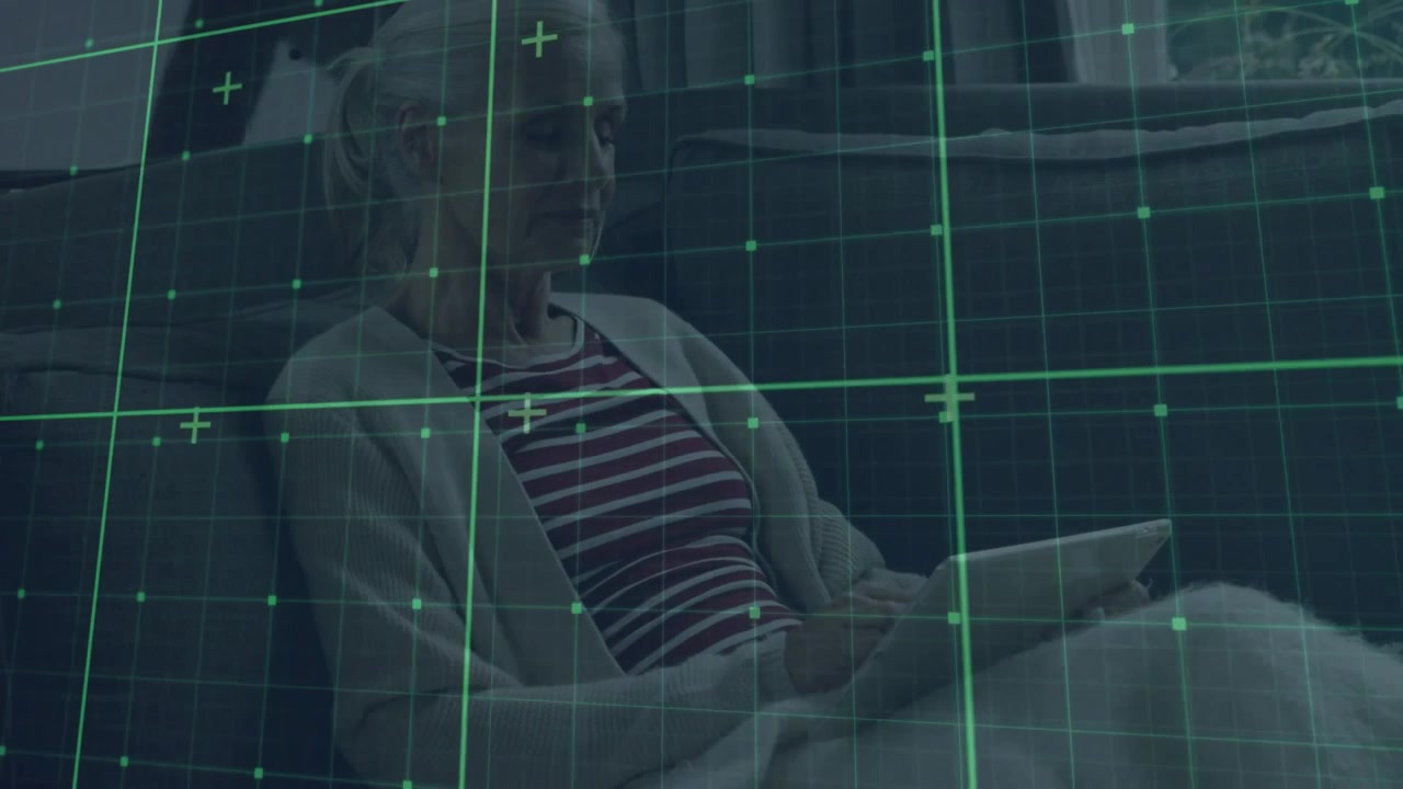 Senior woman holding tablet undergoing medical scan via green grid overlay appearing sweeping torso