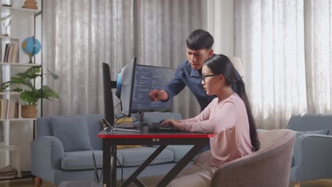 Two people collaborating on a coding project at home.