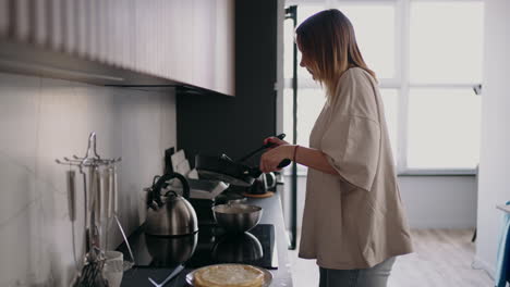 adult woman is frying pan in weekend morning housewife or single lady is cooking breakfast in home