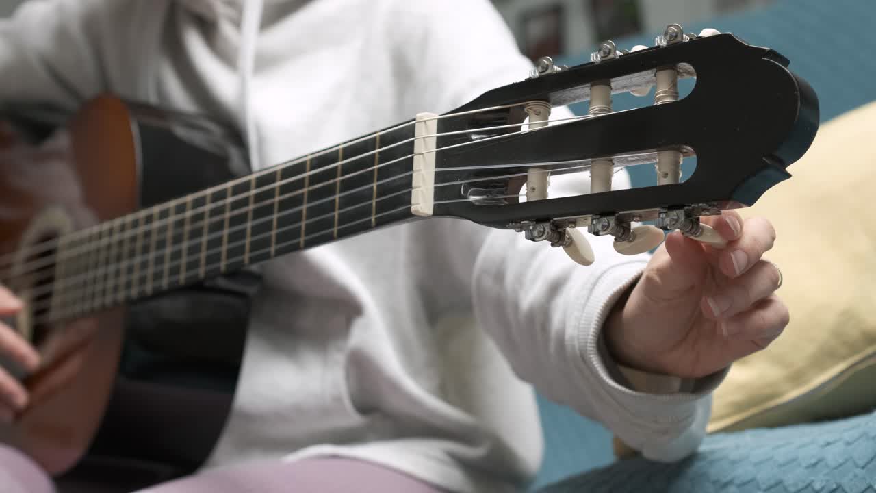 Musician skillfully tuning an acoustic guitar with a white pick