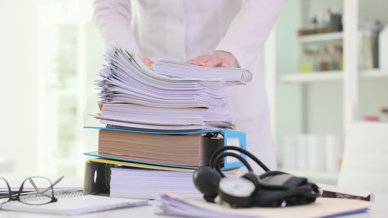 Medical professional handling a large stack of patient records and paperwork