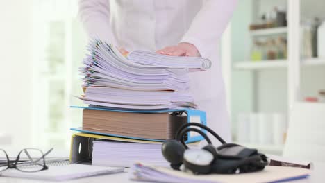 medical professional handling a large stack of patient records and paperwork