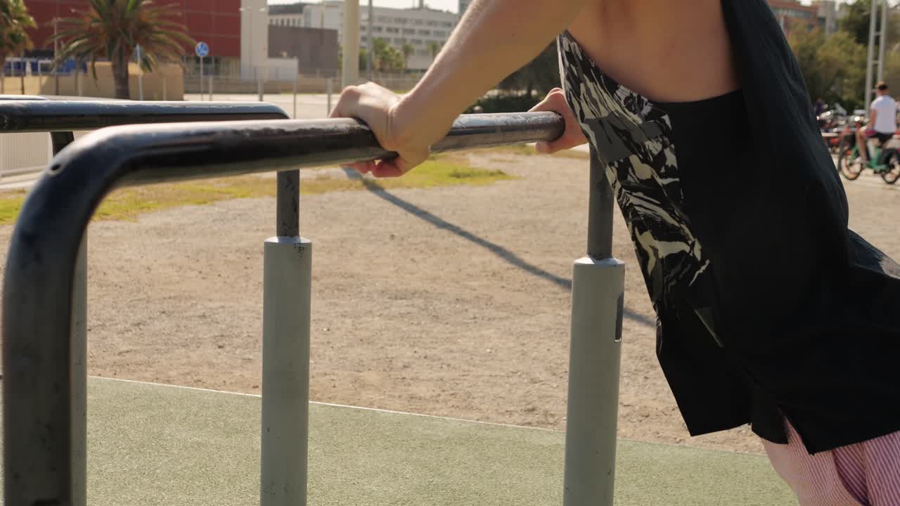 Person working out on outdoor parallel bars in a city park