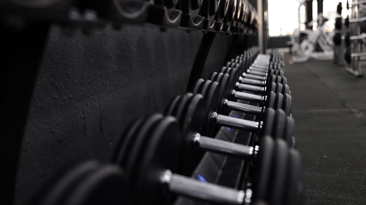 Fila de mancuernas oscuras para ejercitar músculos en un gimnasio moderno