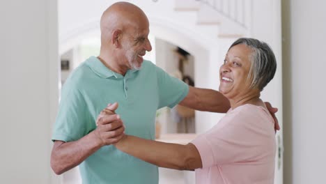 Happy-biracial-senior-couple-having-fun-dancing-together-at-home,-slow-motion