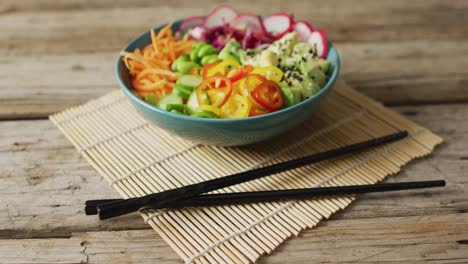 composition of bowl of rice and vegetables with chopsticks on wooden background