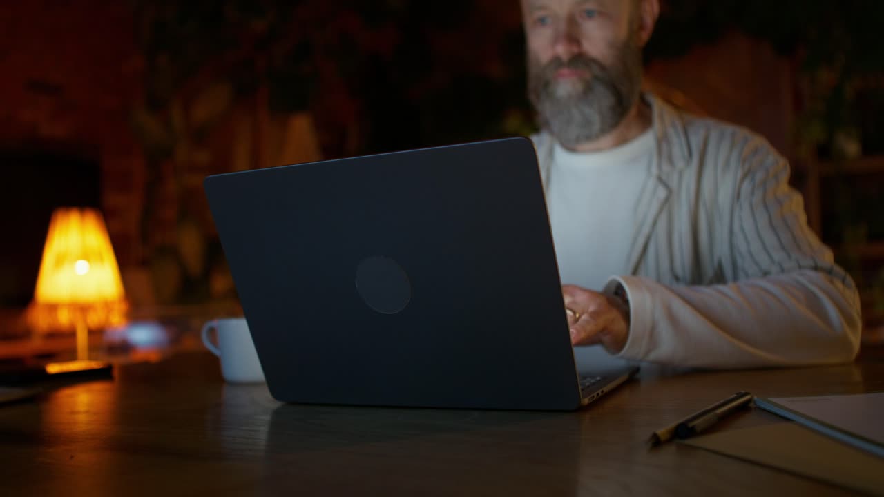 hombre trabajando en la computadora portátil por la noche en su oficina de casa