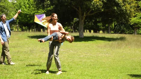 niño pequeño y padres volando una cometa y jugando en el parque