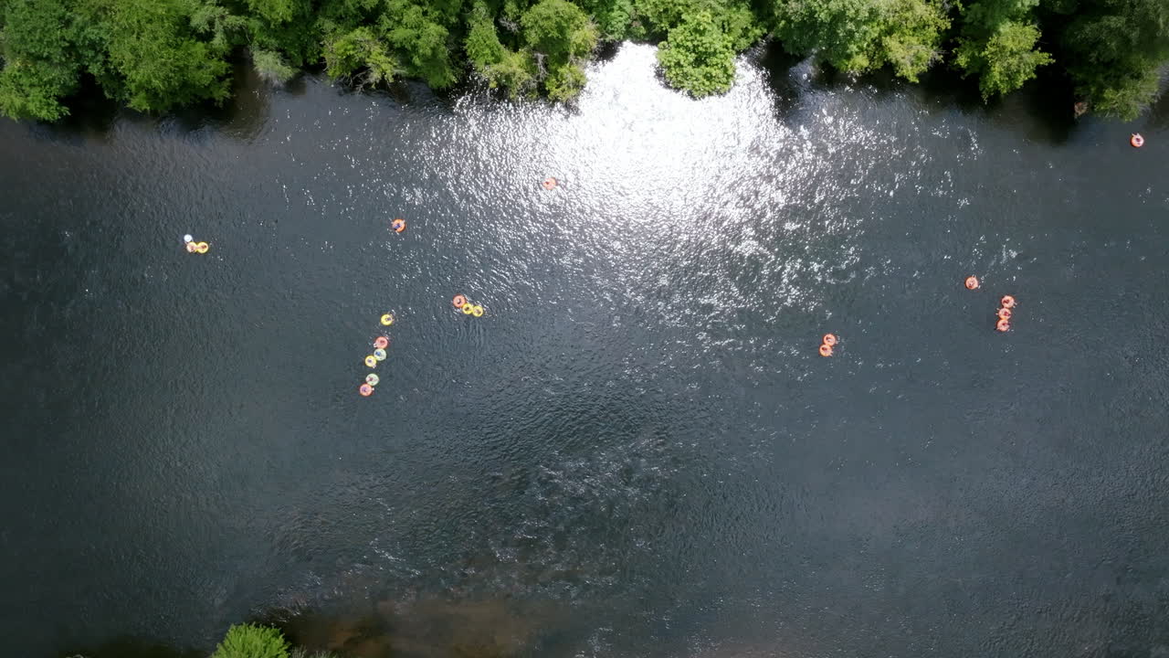 Top down aerial drone footage of people floating down the Hiawassee River in inner tubes in Tennessee during the summer months.