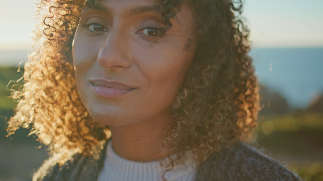 Closeup happy woman posing on evening coastline. Smiling girl looking camera