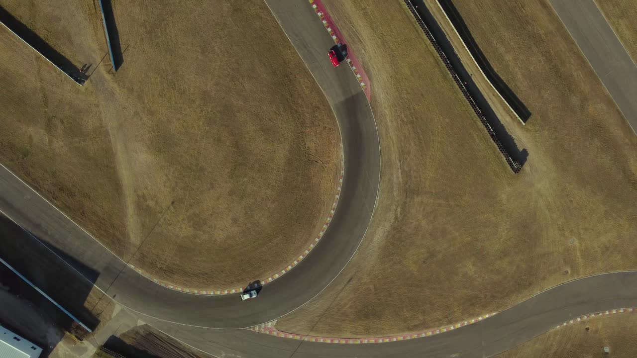 Rotational aerial view of racing cars turning at curve of racing track