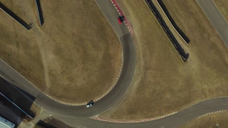 rotational aerial view of racing cars turning at curve of racing track