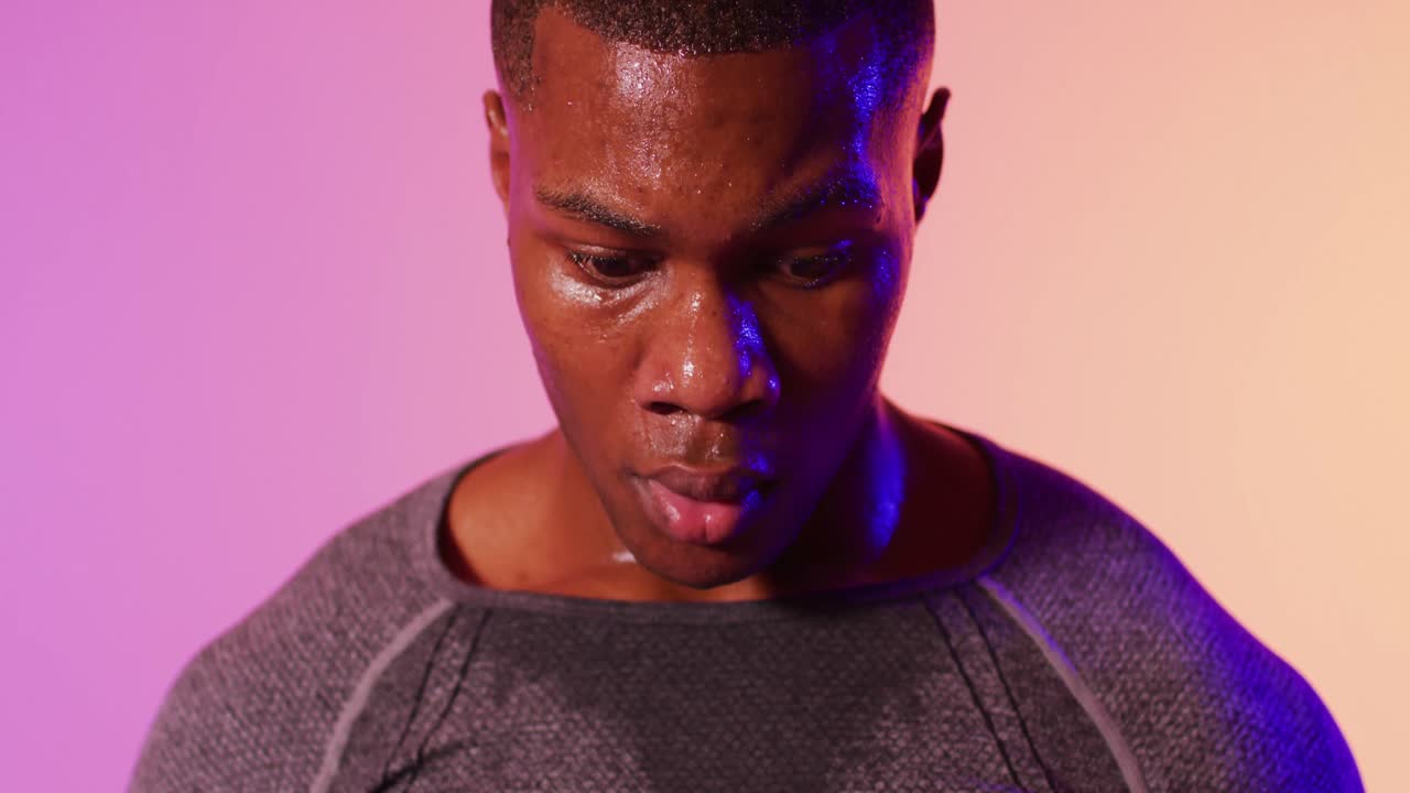 Ritratto di un corridore afroamericano con abbigliamento sportivo sotto un'illuminazione rosa