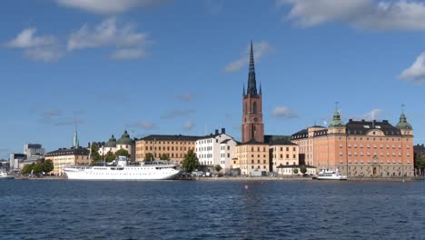 Vista-General-Del-Casco-Antiguo-De-Estocolmo,-Incluidos-Algunos-Barcos,-El-Puerto-Y-La-Torre-De-La-Iglesia-De-Riddarholmen