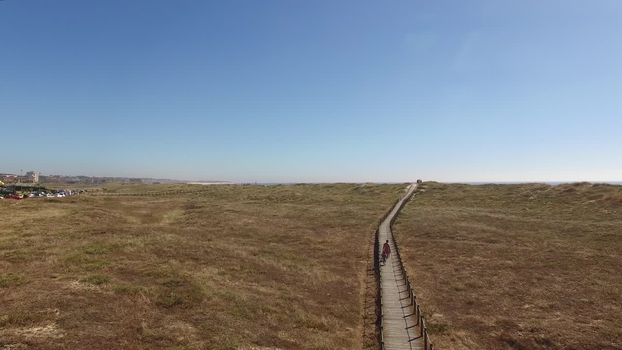 gente en la pasarela en dirección a la vista aérea de la playa