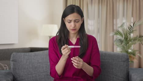 mujer india triste comprobando la prueba de embarazo